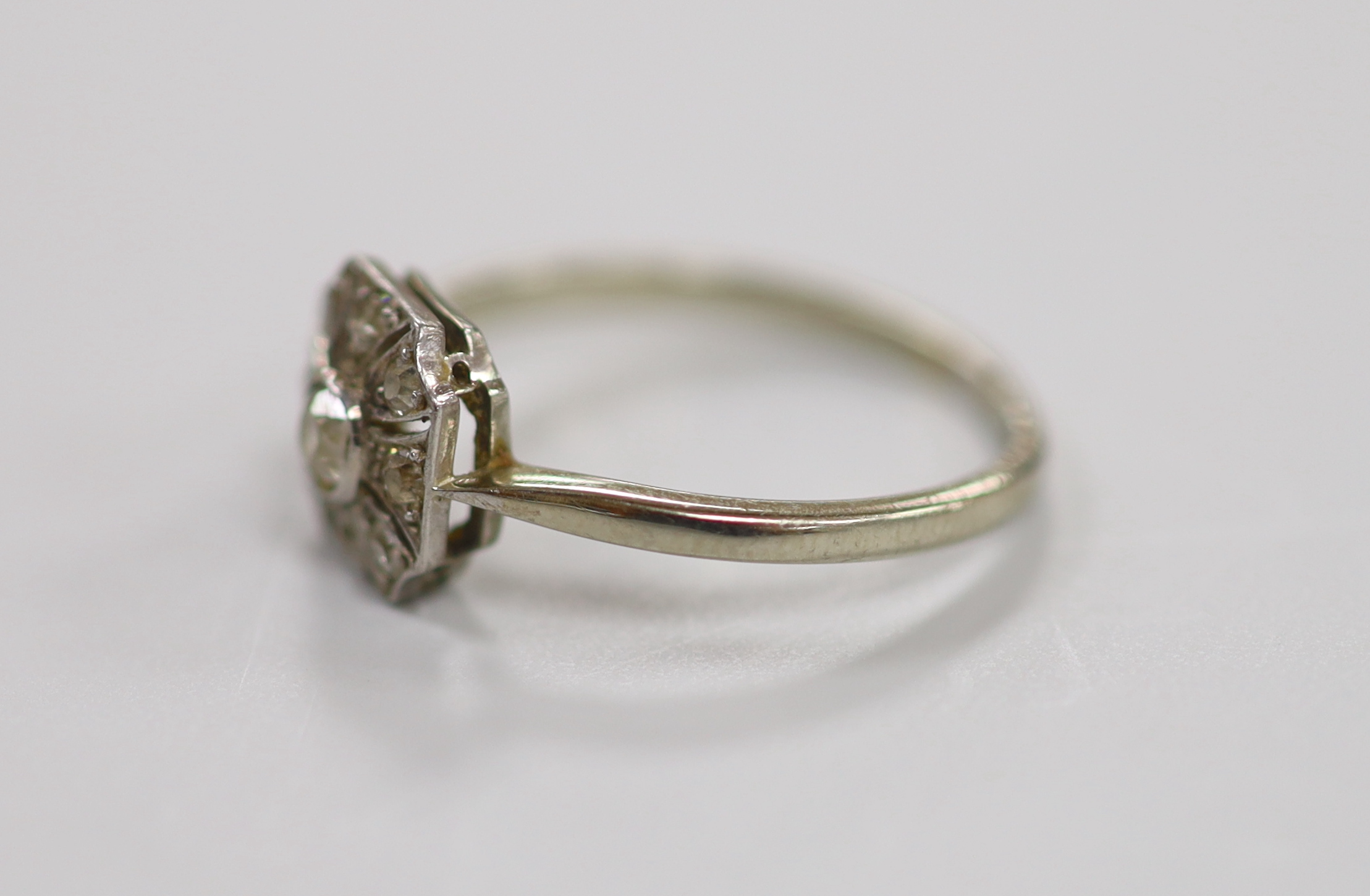 A 1920's white metal (stamped Pt) and nine stone diamond set cluster ring, size O, gross weight 2.4 grams.